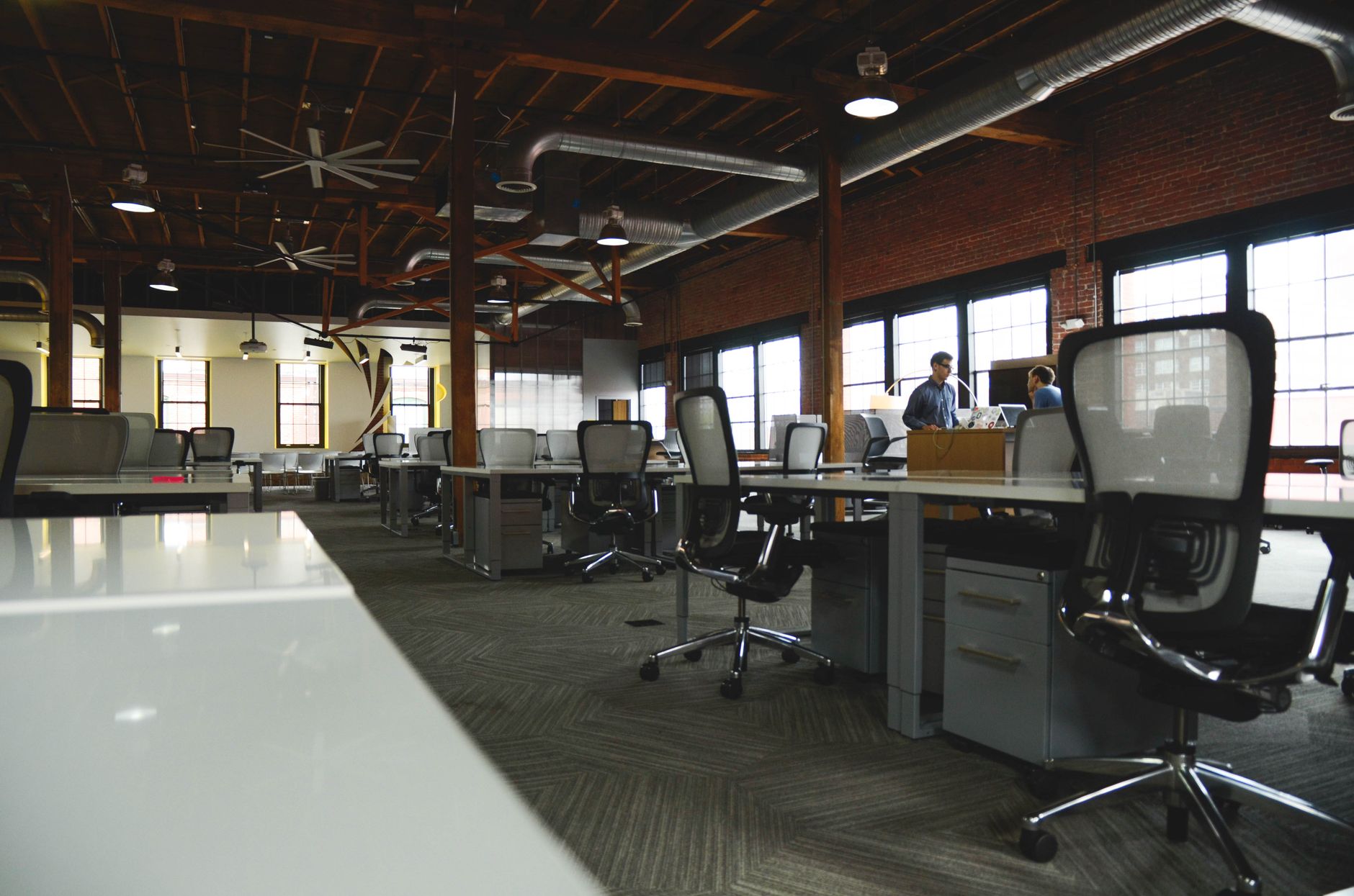 Wide loft workspace with long shared tables and tall windows